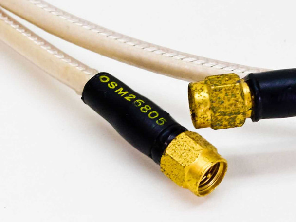 Close-up of SMA male connector ends with gold plating and black strain relief boot labeled OSM26805 in yellow text