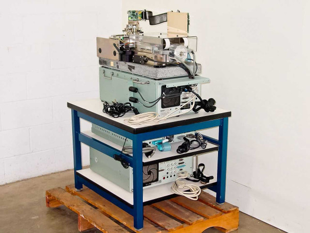 Guzik S1701 SpinStand full system on blue work table with all cables, power supplies, and ancillary components visible on lower shelf