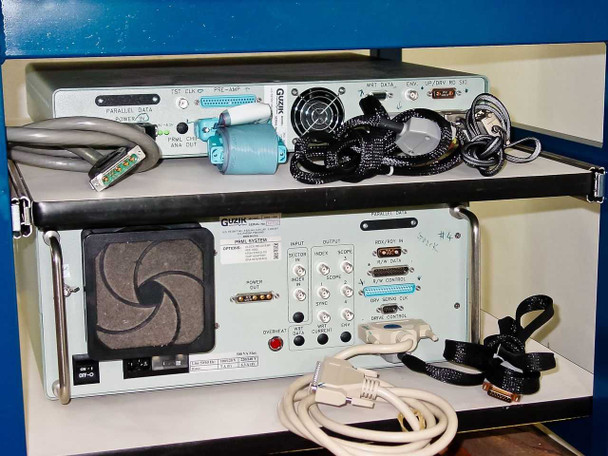 Rear panel of Guzik spinstand electronics chassis showing Parallel Data, PRML DSA outputs, input/output connectors, fans, and bundled cables on lower shelf