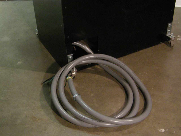 Hevi-Duty HDT-5610 cabinet base rear — gray flexible conduit power cable assembly coiled on floor, cabinet on casters with mounting brackets visible