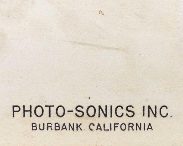 Photo-Sonics film magazine shell — close-up of Photo-Sonics Inc. Burbank California imprint on white exterior showing age patina and surface wear
