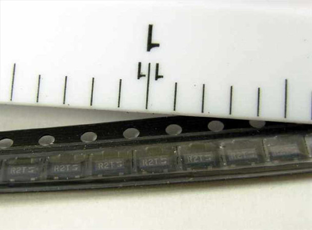 Strip of 10 Fairchild MMBT2222AR-R R2T SOT-23 transistors on tape shown next to ruler for scale