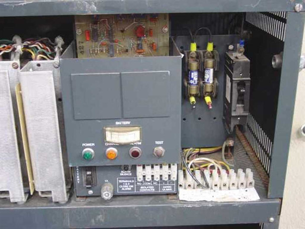 UPS cabinet interior close-up showing charger control panel with Power, Charge, Alarm, Test indicators and terminal strip