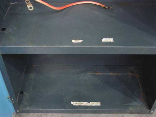 UPS cabinet battery shelf close-up showing empty compartment with caution label and battery cable routing