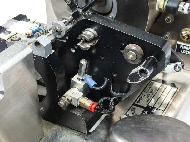 Micro Tooling MT0268 close-up of pneumatic actuator and tooling block showing Clippard fittings, red and blue pneumatic connectors, and bearing feed nozzle area