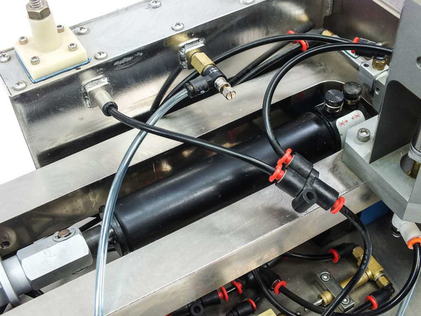 Micro Tooling MT0268 internal close-up of Bimba flat-1 pneumatic cylinder assembly with black manifold, red push-in fittings, and blue/clear pneumatic tubing connections