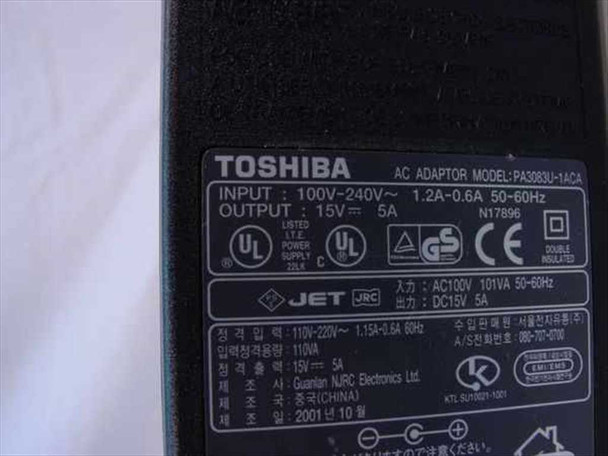 Toshiba PA3083U-1ACA rating label closeup showing INPUT 100-240V 1.2A-0.6A 50-60Hz, OUTPUT DC 15V 5A, UL CE GS certifications, manufactured October 2001 in China