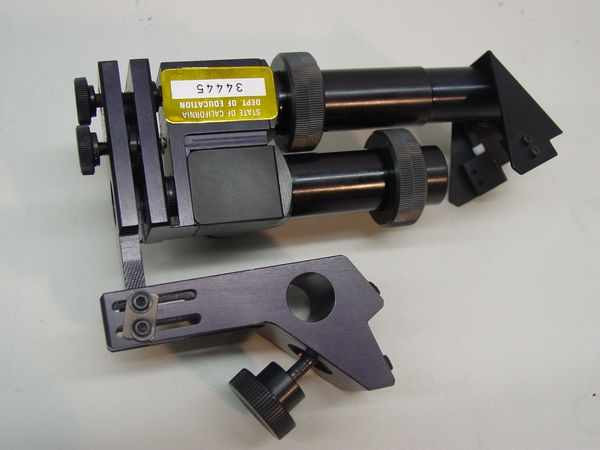 TeleSensory Typewriter Lens Module — front and side view showing precision optical assembly with adjustable mounting arm, black anodized metal body, and government property asset tag