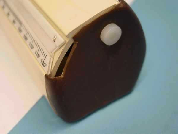 Close-up of brown plastic end cap showing chipped plastic and white button post