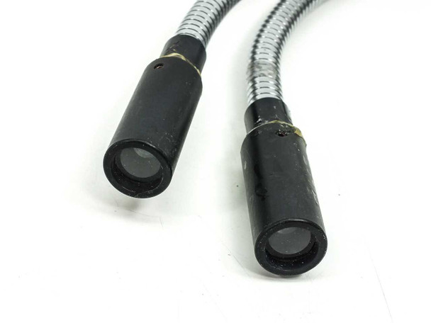 Close-up of both dual output tips showing circular fiber bundle lenses inside black cylindrical housings with yellow tape markers on metal gooseneck arms