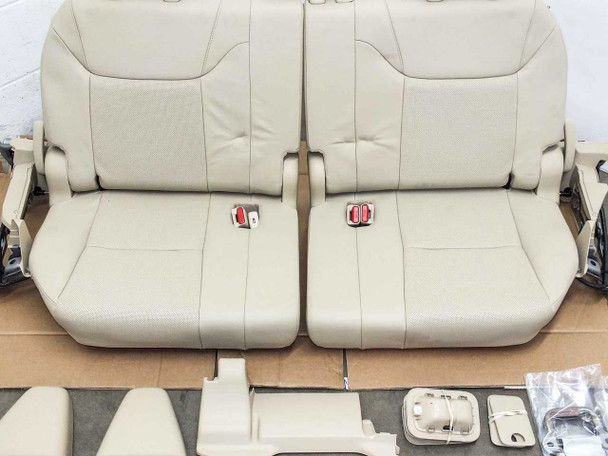 Lexus LX570 3rd row seat assembly — top-down view of two-section beige leather seat cushions with red belt buckles, hinge covers, and hardware bags