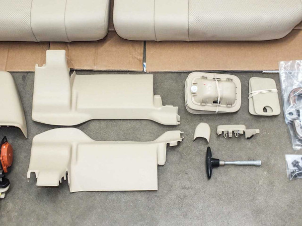 Lexus LX570 rear seat trim components — hinge covers, reclining cover, cushion lock covers, tool, and miscellaneous small parts laid out on floor