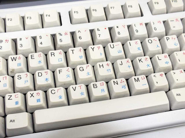 Close-up of dual-language keyboard keycaps — English characters with Traditional Chinese (Bopomofo) secondary legends in red and blue