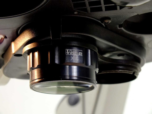 Close-up bottom view of Vision Engineering X4 objective installed in carousel; adjacent empty objective/bulb bay visible to the right