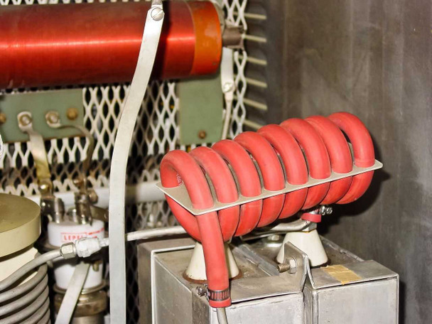 Close-up of red-insulated RF output work coil (helical inductor) mounted on ceramic standoffs inside cabinet