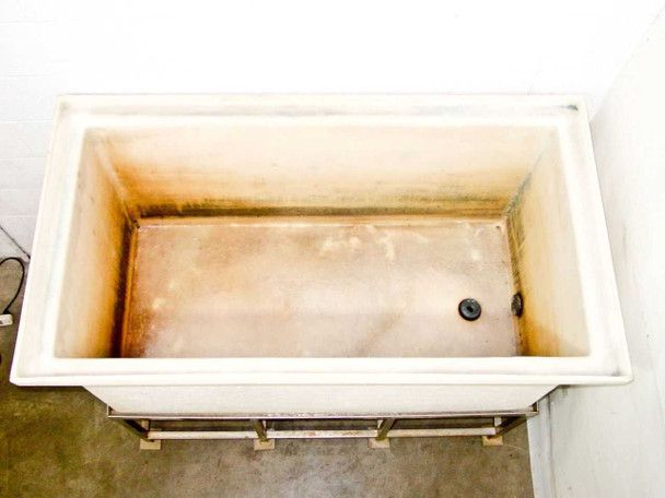 Poly chemical mixing tank — top-down interior view showing chemical staining on walls and bottom drain plug in corner