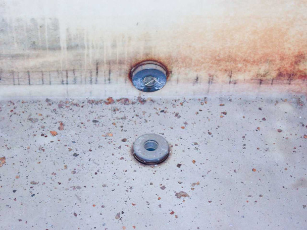 Poly chemical mixing tank — close-up of side outlet fitting and bottom drain plug showing chemical residue staining on tank exterior