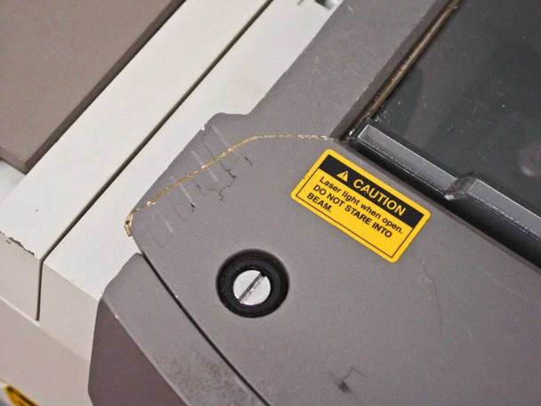 Close-up of crack in plastic housing near the sliding sample compartment door on the Nicolet Magna-IR 560, with laser caution warning label visible