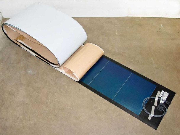 Uni-Solar PVL-116 flexible amorphous solar panel partially unrolled on floor showing blue photovoltaic cells and MC3 cable connections on backing