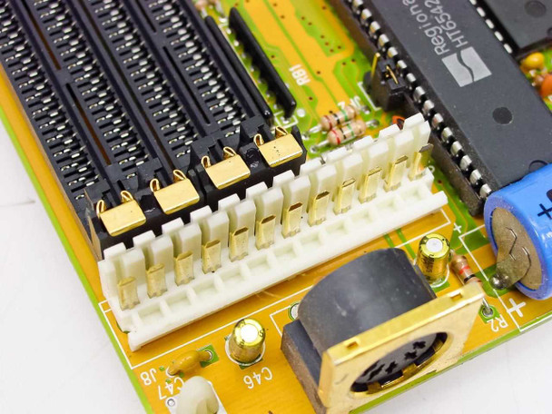 Close-up of M396F motherboard power connector area showing white AT power connector, 5-pin DIN keyboard port, and nearby ICs including a Hyundai chip