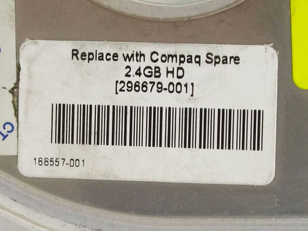 Close-up of Compaq spare label reading 'Replace with Compaq Spare 2.4GB HD 296679-001' with barcode 166557-001
