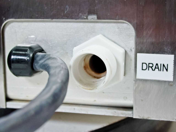 Titertek Zoom drain port close-up showing large white drain fitting and connected drain tubing with rust staining inside fitting