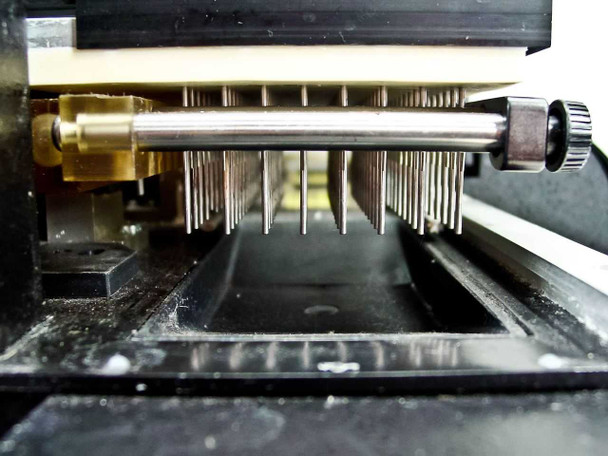 Titertek Zoom 96-pin stainless steel wash needle manifold close-up from below showing individual aspirate/dispense needles and trough