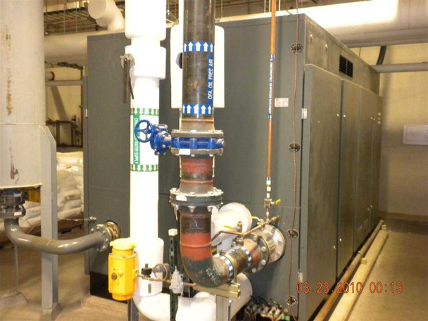 Atlas Copco ZH6-5 compressor — side view showing large flanged pipe connections, blue gate valve, red valve assembly, and instrumentation piping on the air inlet/outlet side