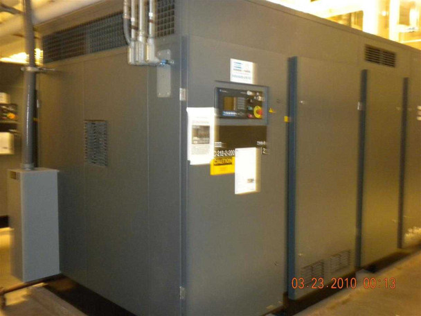Atlas Copco ZH6-5 compressor — corner panel view with secondary control panel, emergency stop, warning labels, and partial model number data plate visible