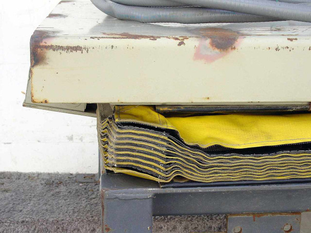 Close-up of SL35 scissor lift yellow and gray accordion bellows skirt showing layered fabric construction and platform edge with rust and chipping paint