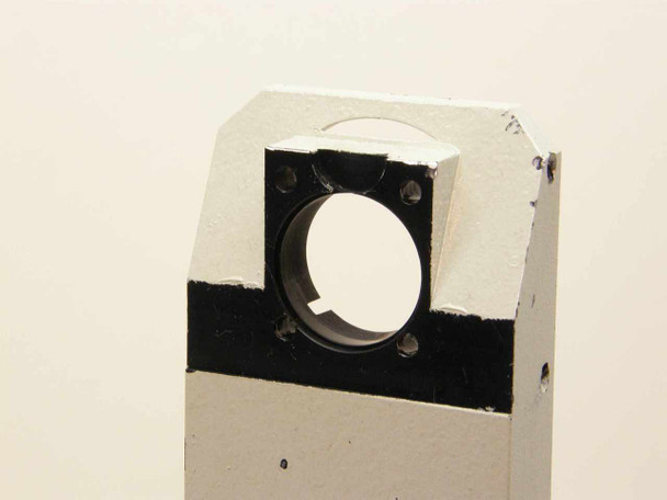 Close-up of upper mounting block showing circular bore with 4 screw holes and heavy paint chipping around edges