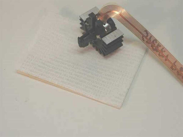 Sperry P80RA 9-pin dot matrix printhead with attached flat copper ribbon cable, shown on white foam packing material
