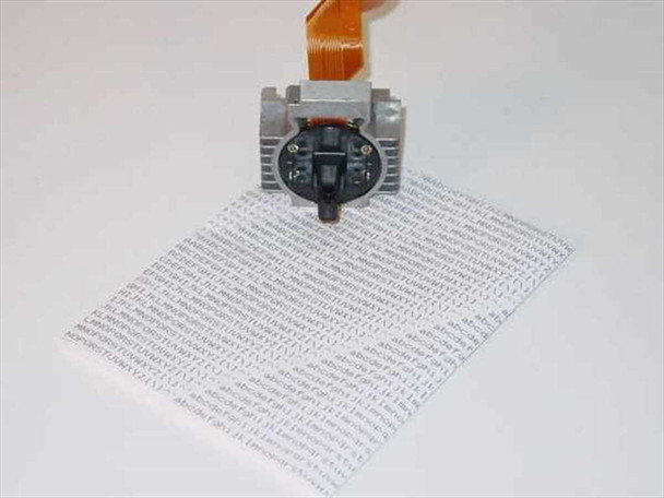 Pitney Bowes J083 dot matrix printhead with flex ribbon cable, shown resting on a printed test page sample