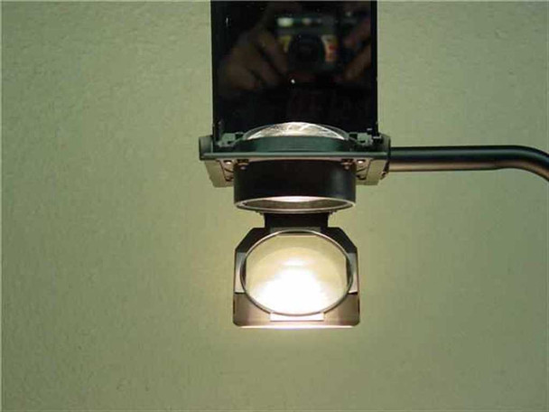Close-up of Dukane 663 projection head lens assembly lit from below, showing fresnel condenser lens and lamp illuminated