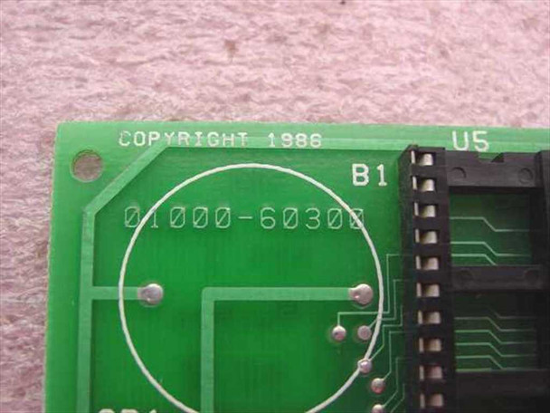PCB close-up showing silkscreened copyright 1986 date and part number 01000-60300 on green circuit board