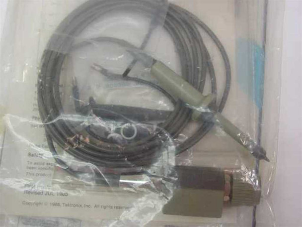 Tektronix P6106A probe body, coaxial cable, ground lead, and accessories visible through open bag alongside printed safety and copyright sheet