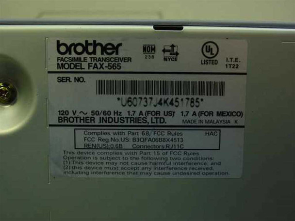 Brother FAX-565 bottom label showing model FAX-565, serial number, 120V 50/60Hz 1.7A rating plate, FCC compliance, and Made in Malaysia marking