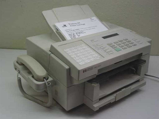 HP C2136A FAX-310 facsimile machine front view with handset, ADF loaded with Windows XP printer test page, and paper output tray