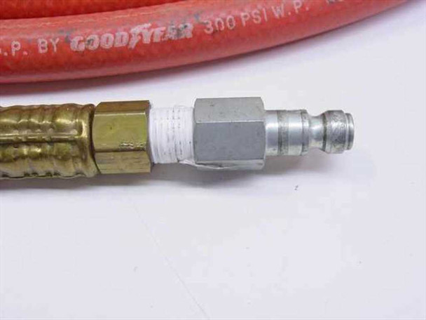 Close-up of Goodyear 3117 air hose end showing brass male fitting, hex adapter, and steel quick connect plug — hose marked 300 PSI W.P.
