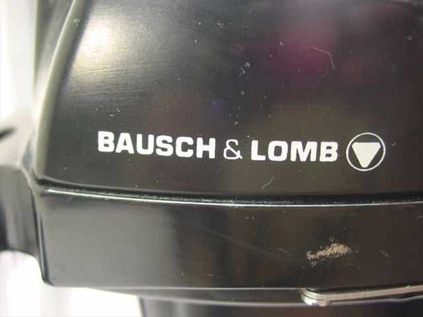Close-up of Bausch & Lomb logo and branding on microscope housing, showing minor scuffing on black body