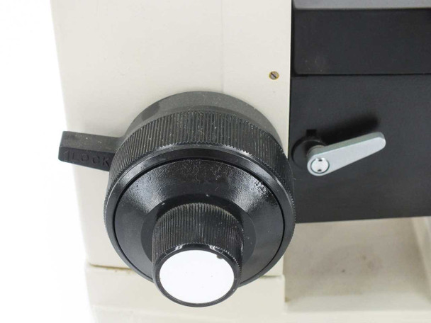 Olympus BHM microscope coarse focus knob close-up — left side of arm with locking lever visible