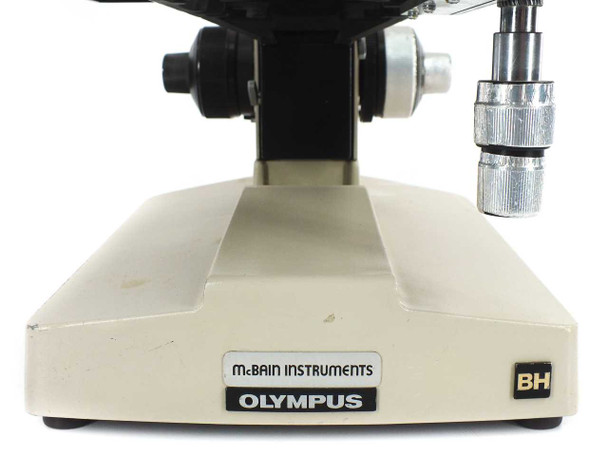 Olympus BH microscope base close-up showing McBain Instruments and Olympus branding labels with BH badge