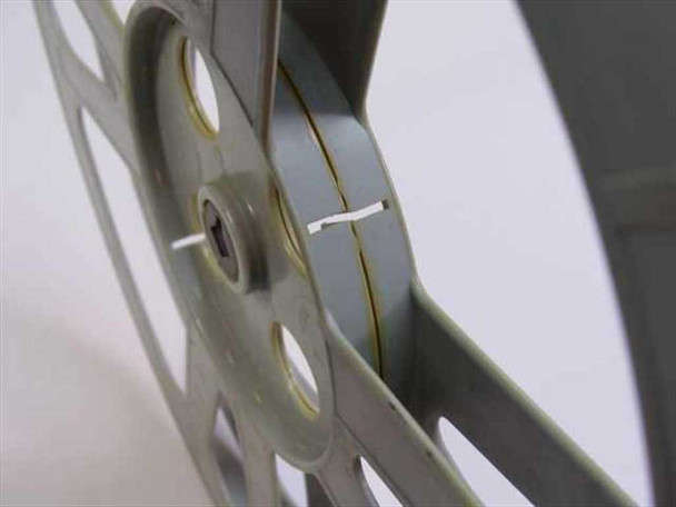 Side edge view of light gray 16mm film reel with a small roll of leader/tape wound on the hub, showing the reel profile and film gate slot