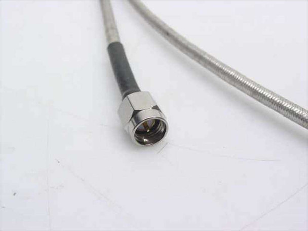Close-up of SMA male connector on semi-rigid coaxial cable showing center pin and threaded coupling nut with braided sheath transition