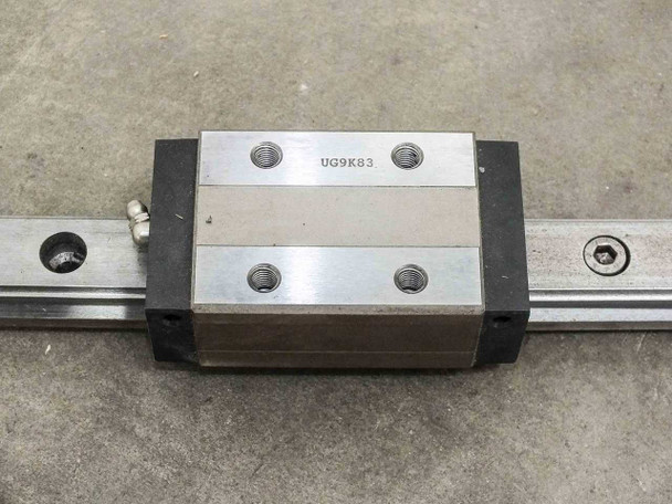 UG9K83 pillow block carriage close-up showing recirculating ball bearing block and grease fitting on rail