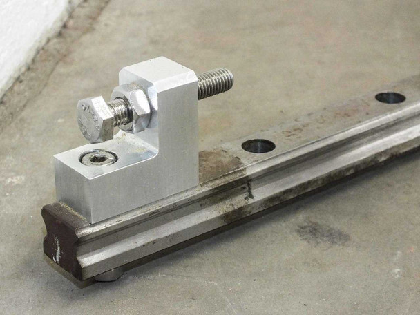 UG9K83 linear guide rail end detail showing aluminum end stop bracket with bolt and rail mounting holes