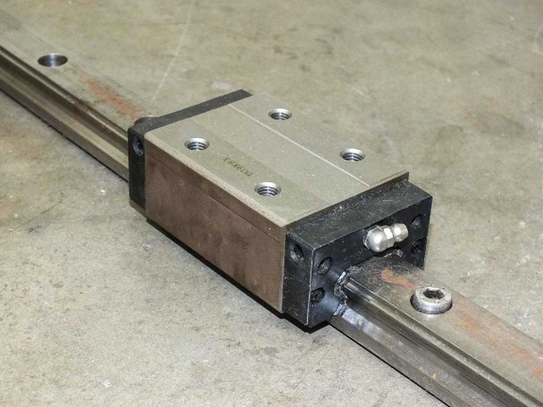 UG9K83 second pillow block carriage close-up showing block body, grease nipple fitting, and rail interface