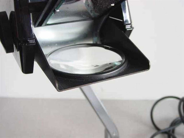 Close-up of 3M 5088 projection head showing round condenser/objective lens mounted in black housing on folding arm