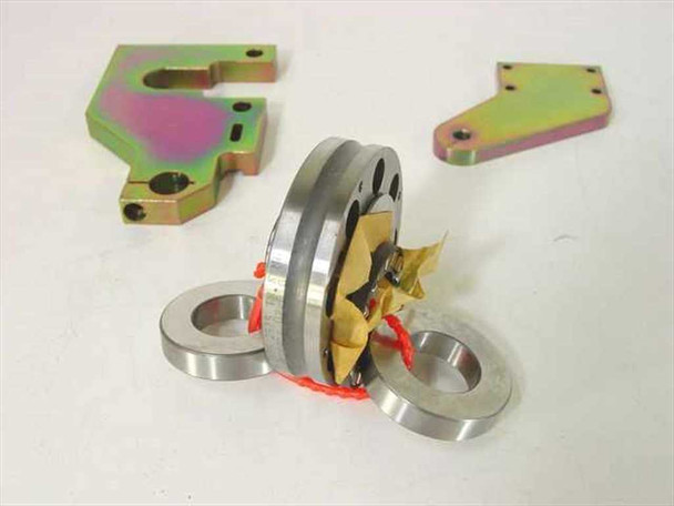 INA ZARF 2575 LTN bearing assembly with needle roller cage, two thrust washers, red retainer clip, and yellow protective wrap — two zinc-chromate mounting brackets in background