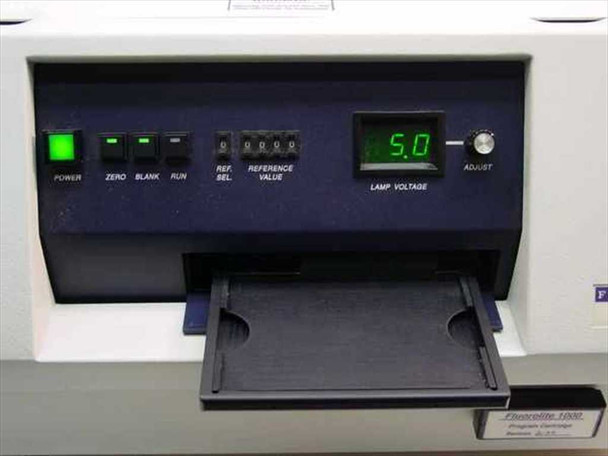 Dynatech Fluorolite 1000 – front control panel detail showing Power, Zero, Blank, Run buttons, Reference Sel and Reference Value switches, and Lamp Voltage digital display reading 5.0